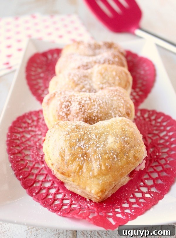 Two Heart Shaped Strawberry Cheesecake Puff Pastry Pies on a wooden board
