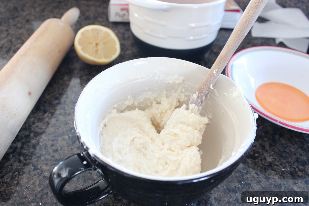 Mixing cream cheese, confectioners sugar, and vanilla extract for cheesecake filling