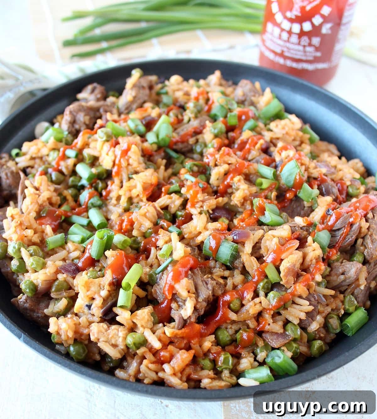 Delicious Sriracha Steak Fried Rice ready in a pan, garnished with fresh green onions