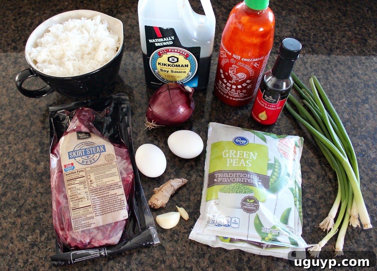 Ingredients laid out for Sriracha Steak Fried Rice, including steak, rice, peas, onions, and sauces