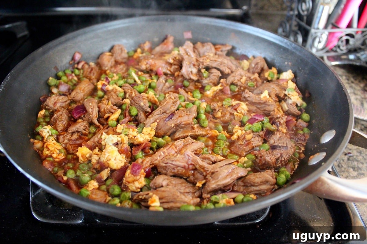 Searing skirt steak in a pan with fried rice ingredients on the side