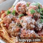 cooked meatballs on top of spaghetti and tomato sauce in bowl with fork