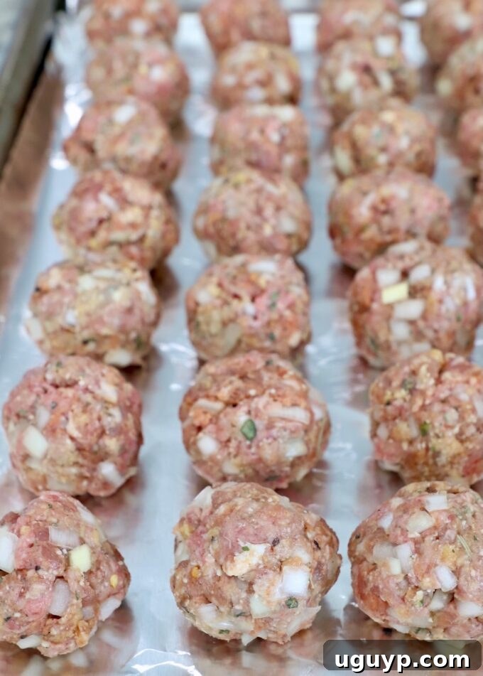 uncooked meatballs on foil lined baking sheet