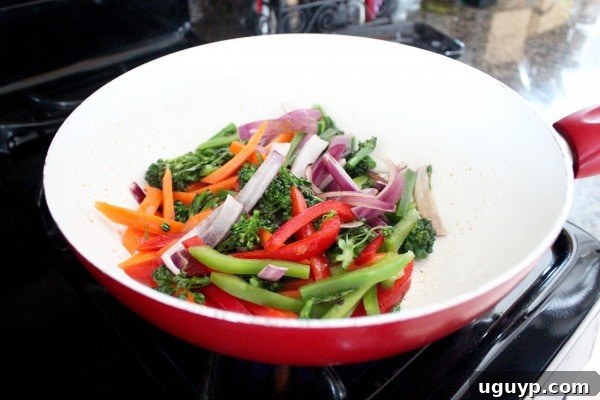Sautéing carrots, onion, bell peppers, and broccoli in a wok