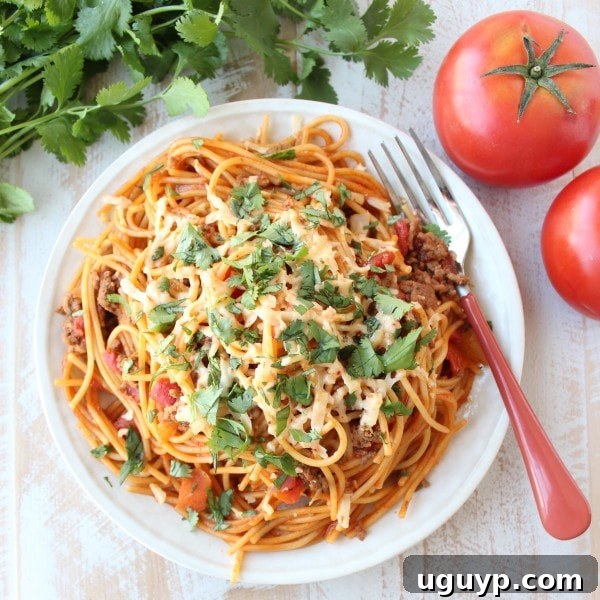 One Pot Buffalo Taco Spaghetti with a fork ready to scoop, served on a white plate with a clean, appealing presentation.