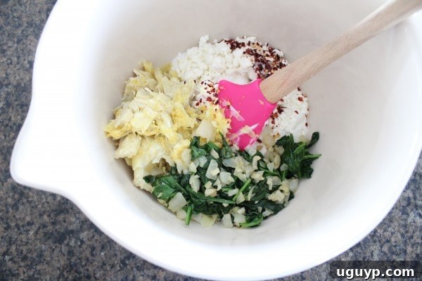 Artichoke hearts, cooked spinach, Greek yogurt, and goat cheese in a mixing bowl