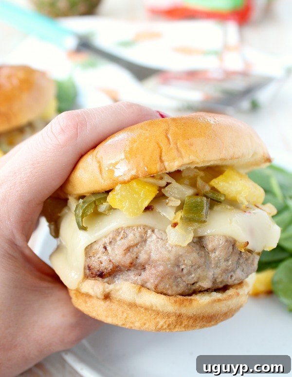 Close-up of a Hawaiian Turkey Burger showing the golden-brown patty, melted pepper jack cheese, and the colorful pineapple jalapeno relish.