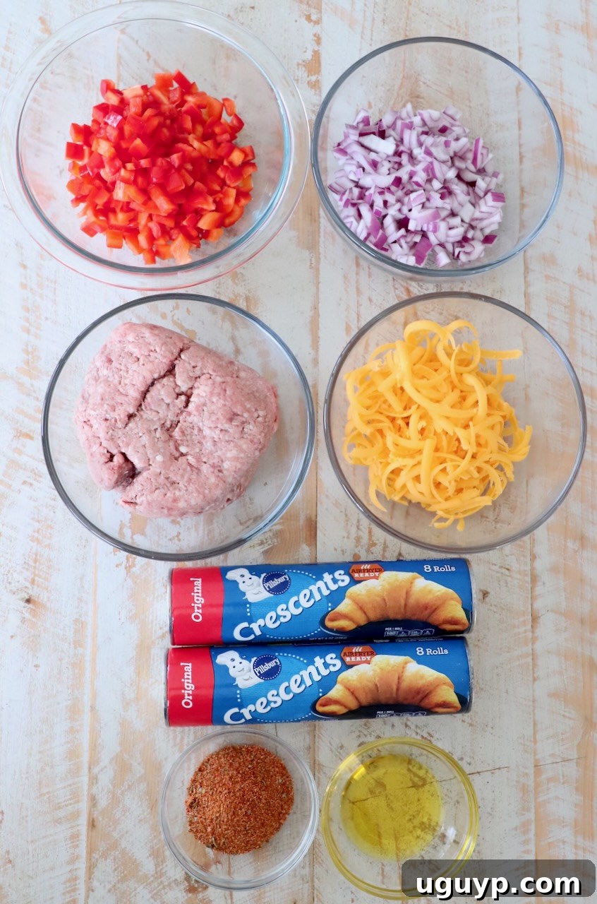 Assortment of fresh ingredients for a crescent roll taco ring laid out on a white wooden board, including crescent roll cans, ground beef, bell peppers, onions, cheese, and taco seasoning.