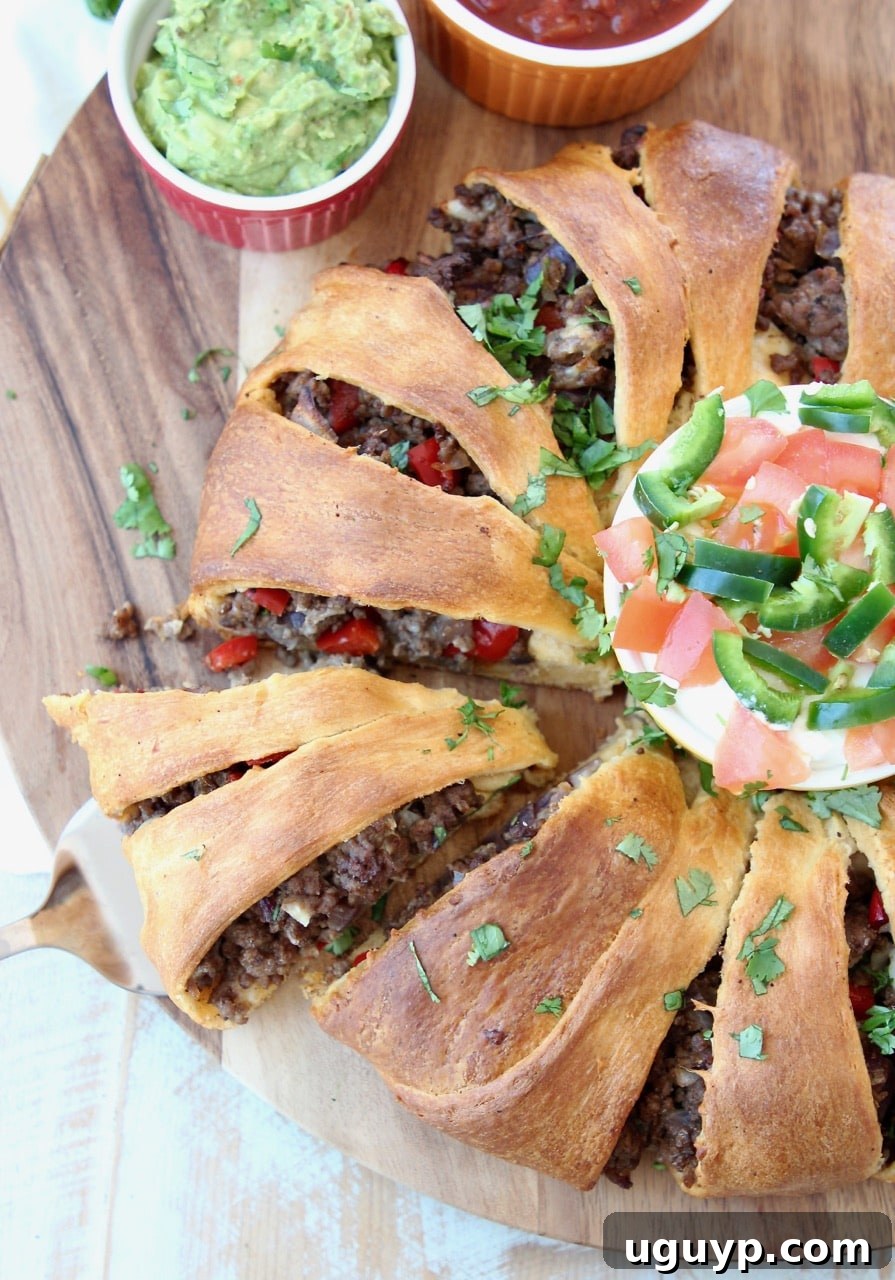 A vibrant and golden taco ring, crafted with Pillsbury crescent roll dough and generously filled with savory taco-seasoned ground beef. A slice has been carefully cut out, showcasing the delightful layers and rich filling within.