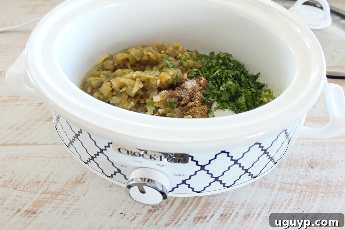 Diced green chilies, cilantro, and various spices being added to a crock pot