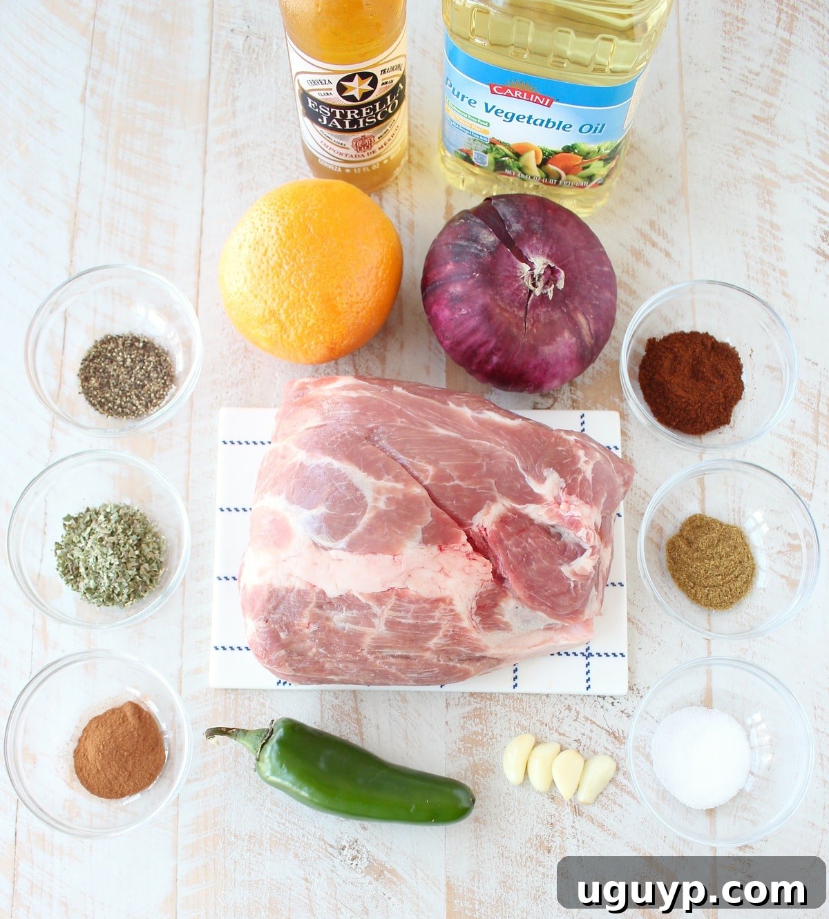 A beautifully arranged selection of fresh ingredients for slow cooker carnitas on a white wooden board, highlighting the quality and freshness.