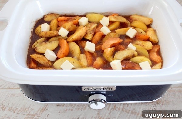 cooked sliced fruit in a crock pot with sugar and cubes of butter
