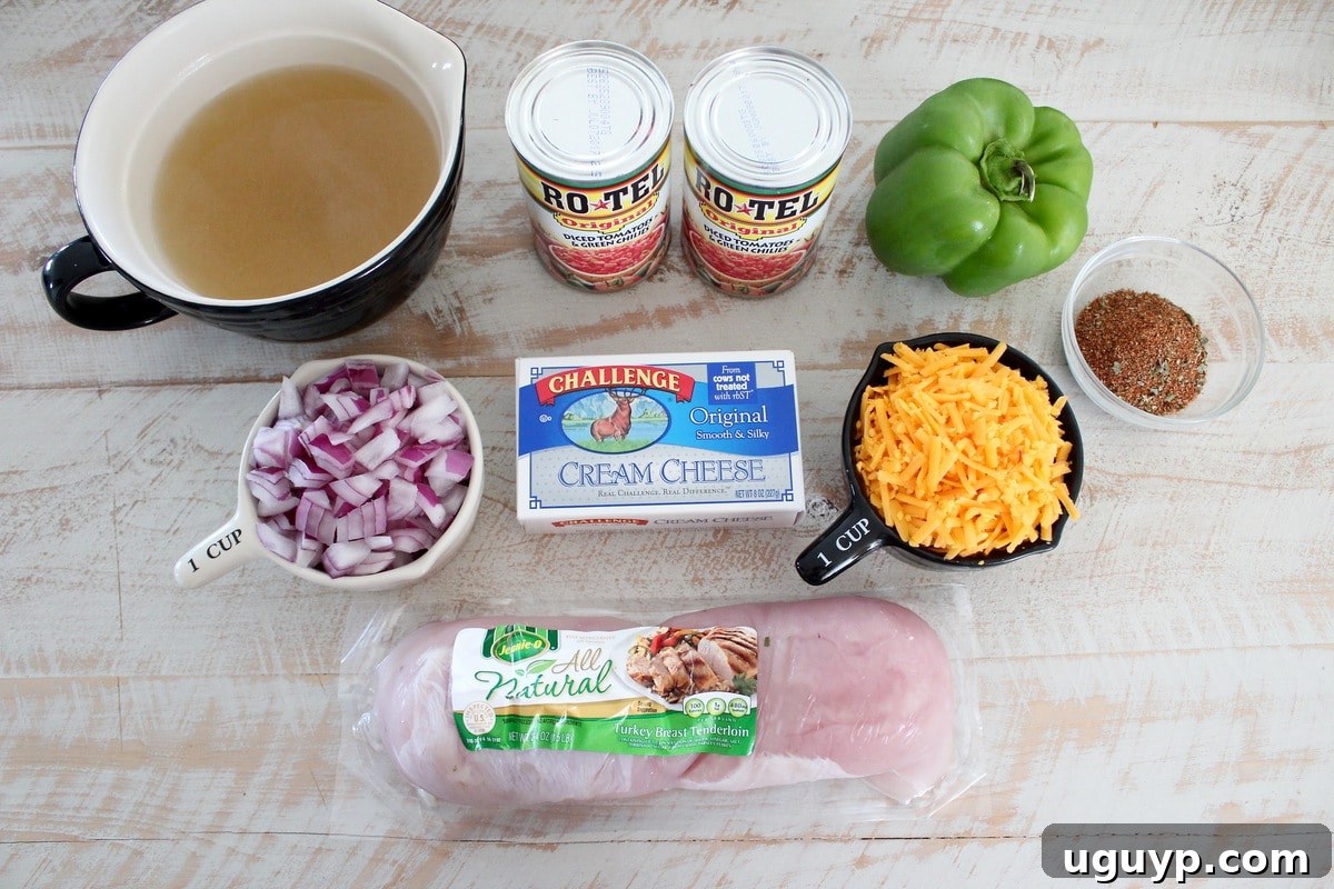 Cheesy Turkey Taco Soup Recipe Ingredients laid out on a wooden board: turkey, taco seasoning, onion, bell pepper, canned tomatoes, chicken broth, cream cheese, and shredded cheddar.