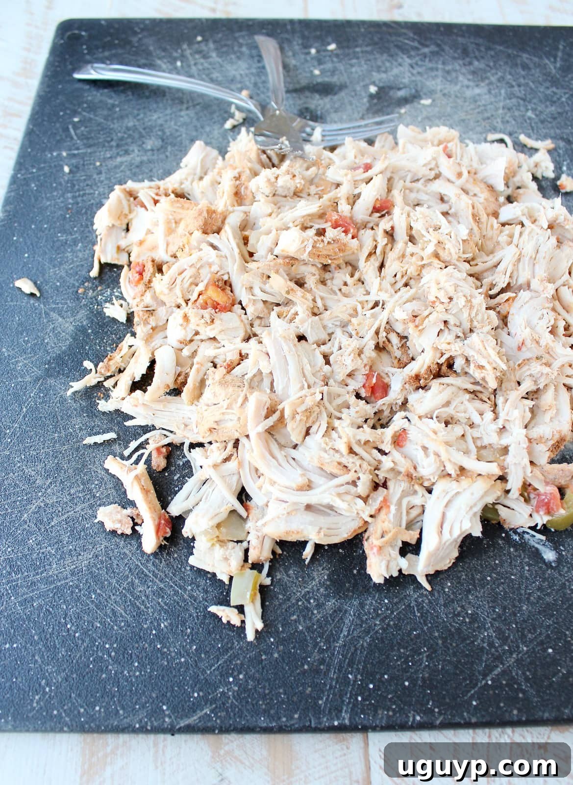 Shredded turkey meat on a black cutting board, ready to be returned to the soup.