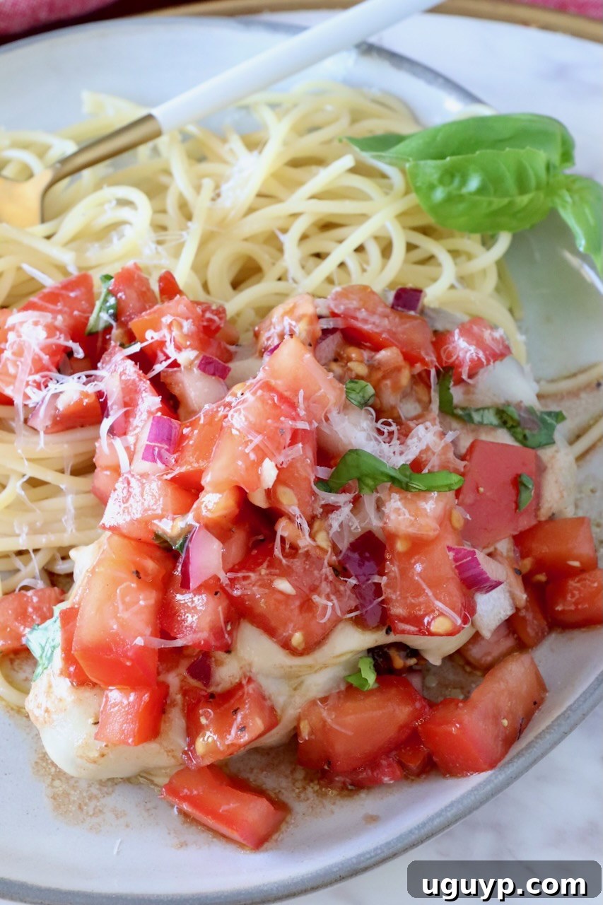 cooked chicken on a plate next to spaghetti noodles covered with tomato bruschetta