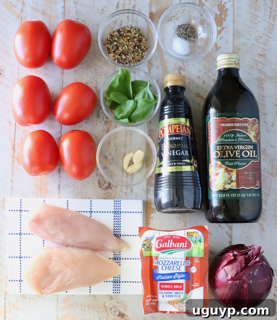 ingredients for bruschetta chicken on a white wood board