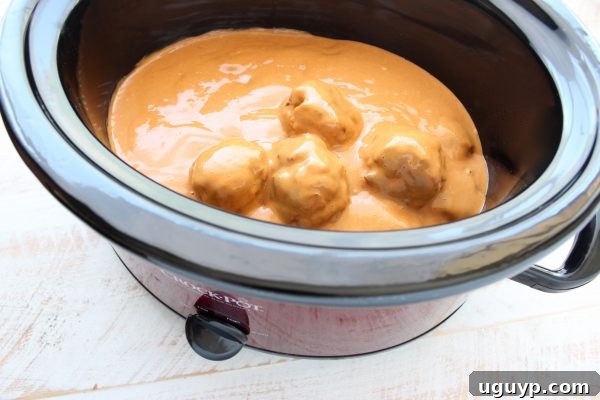 Hearty turkey meatballs generously coated in a rich, creamy peanut sauce, simmering in a slow cooker.
