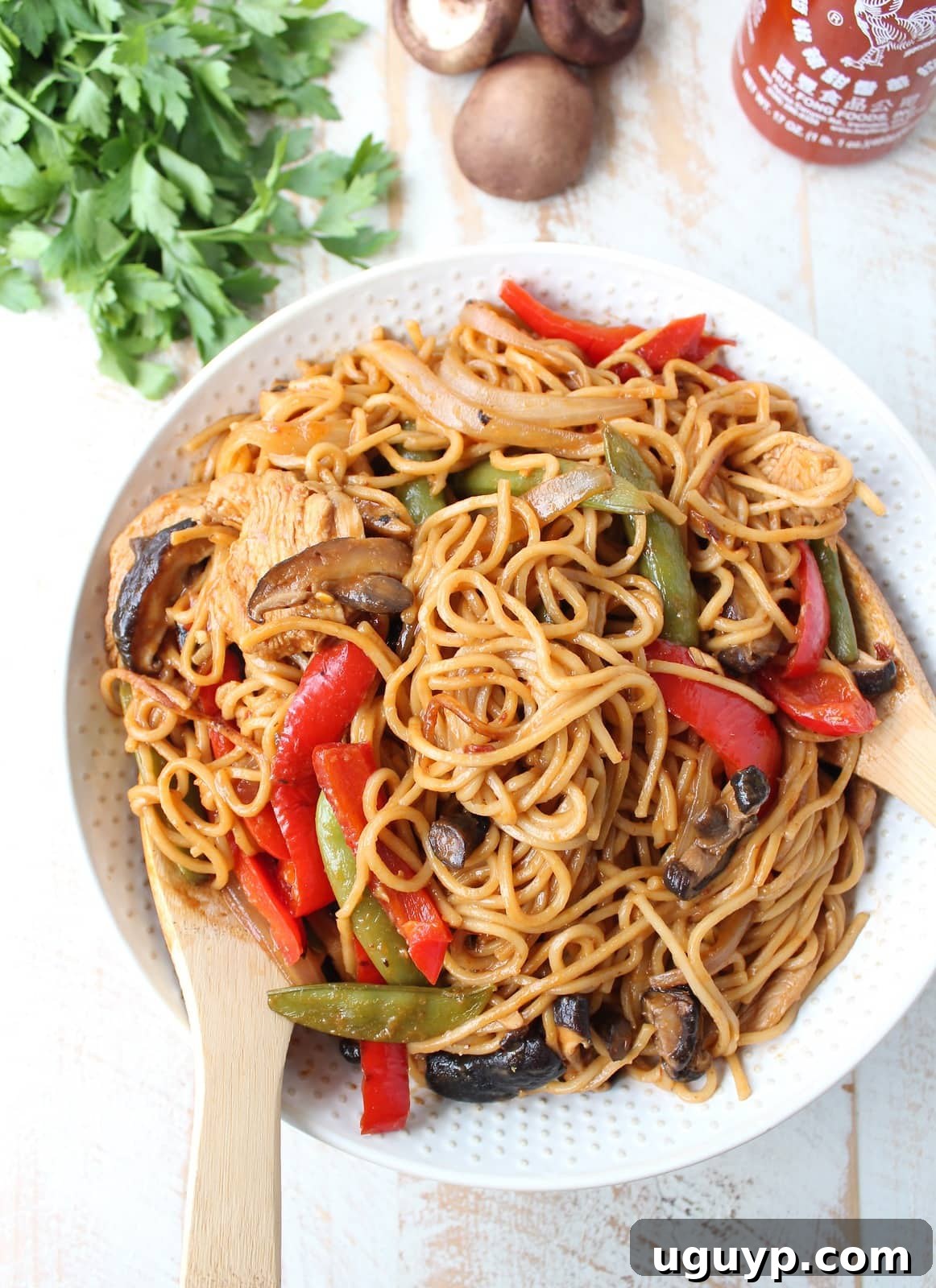prepared chicken lo mein with vegetables in a bowl with serving spoons