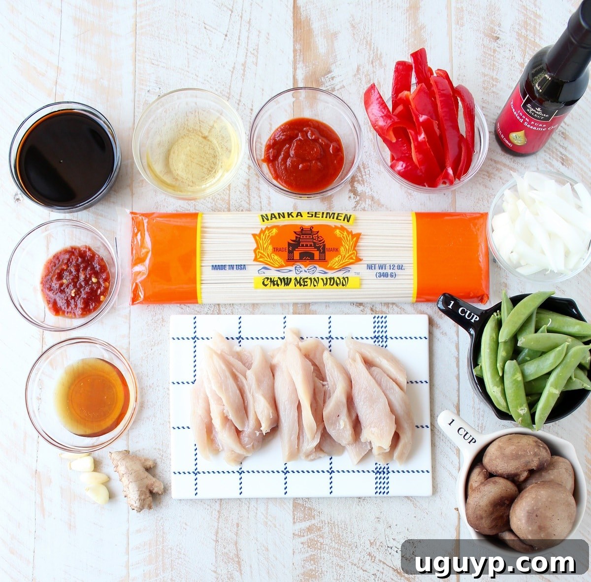 ingredients for chicken lo mein on a white wood board