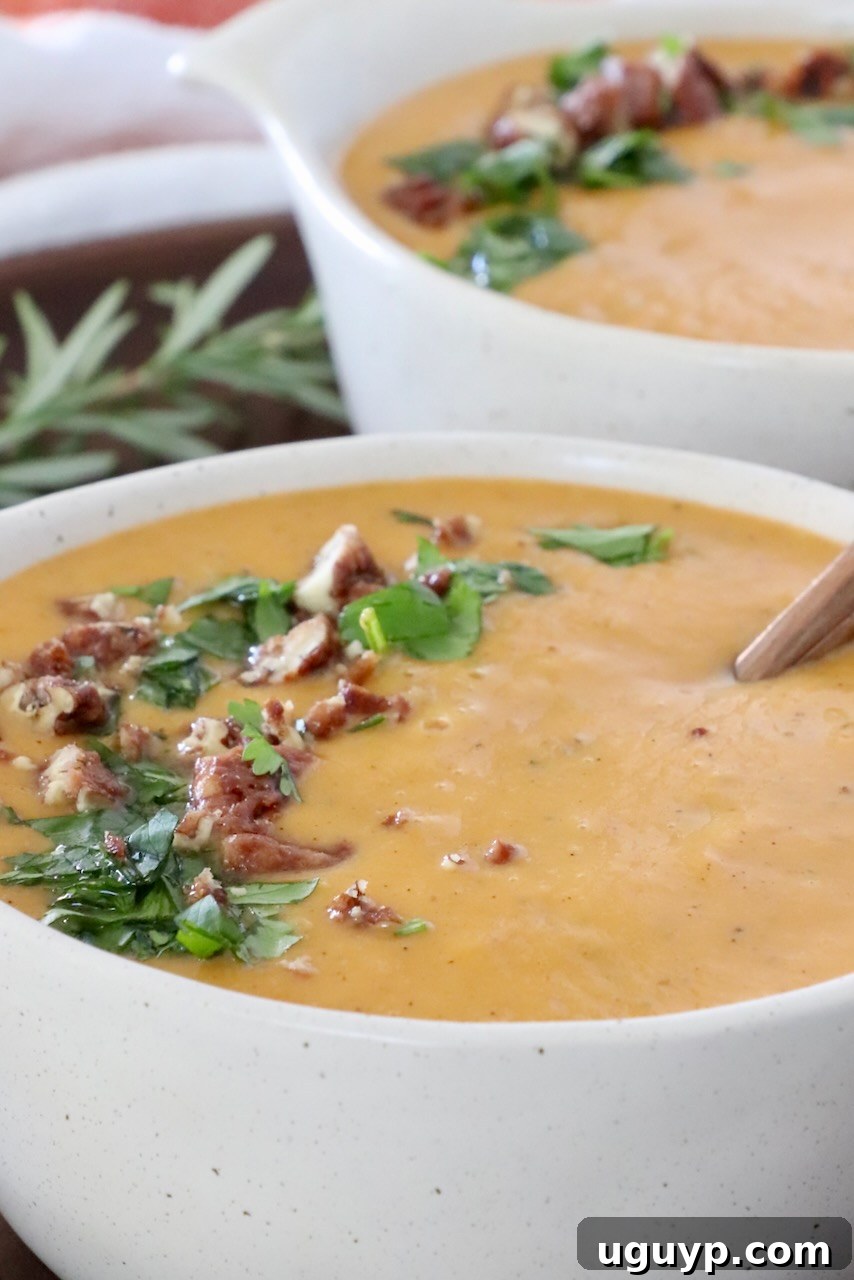 Creamy sweet potato soup served in rustic bowls, garnished with chopped fresh parsley and toasted nuts, ready to eat.