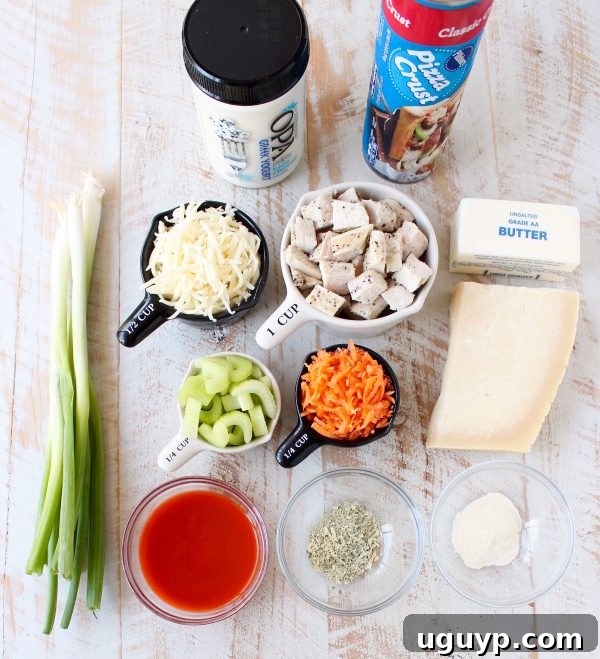 Carefully arranged ingredients for Buffalo Chicken Bake in various bowls and measuring cups on a clean wooden surface, ready for assembly.