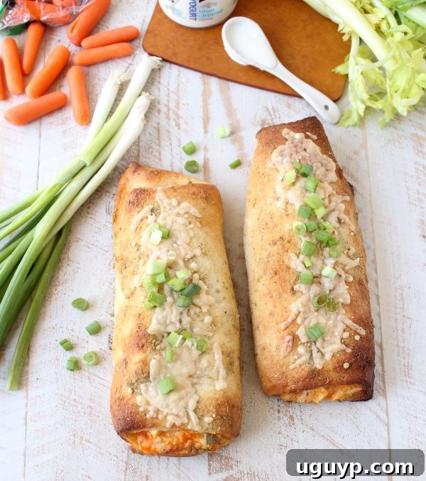 Two cooked Chicken Bakes on a wooden surface next to carrots and green onions.