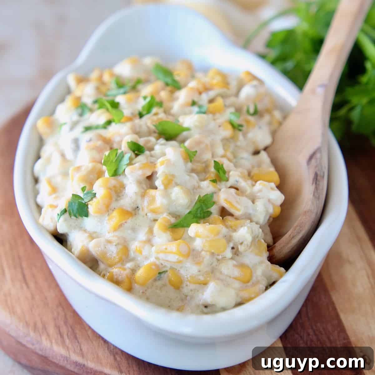 Creamed corn in white oval serving dish with wooden spoon