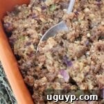 Sausage stuffing in a casserole dish with a serving spoon, ready to be enjoyed