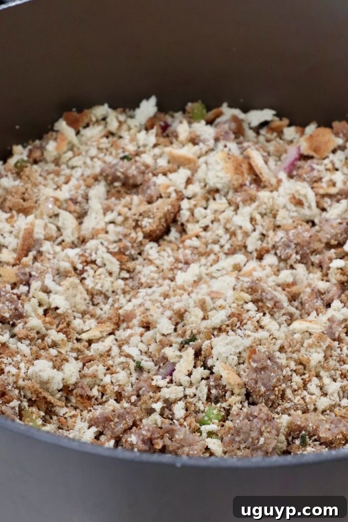 Crumbled sausage and dry stuffing bread crumbs combined in a large pot, ready for liquid ingredients