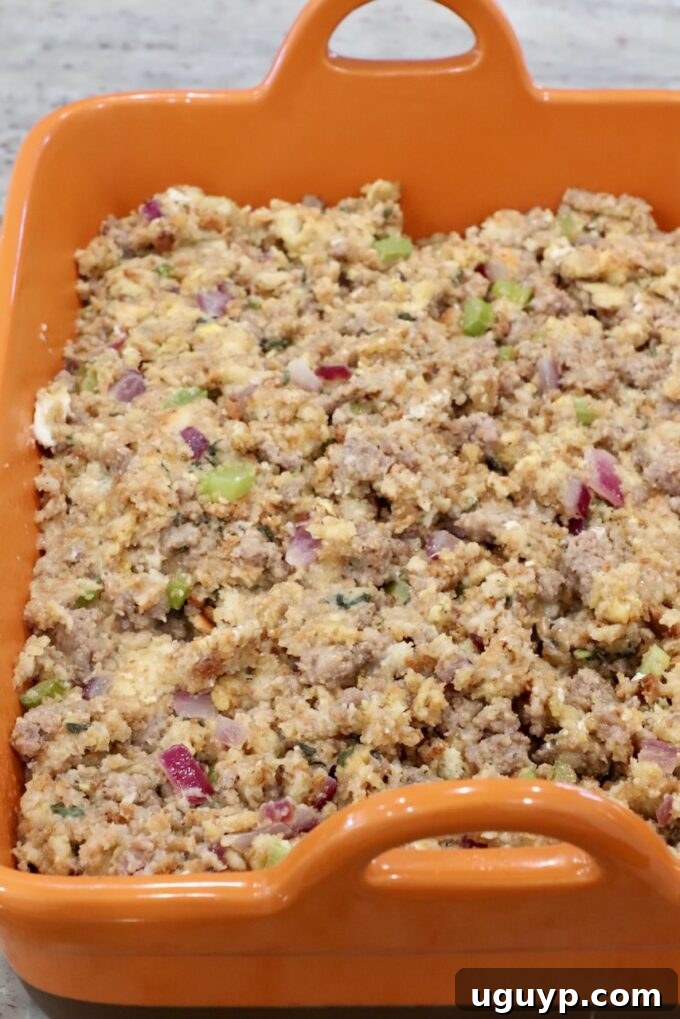 Uncooked sausage stuffing mixture transferred into a casserole dish, ready for the oven