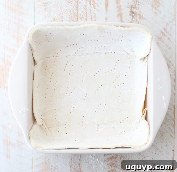Puff pastry dough neatly pressed into the bottom of a square baking dish, creating the base for the pot pie.