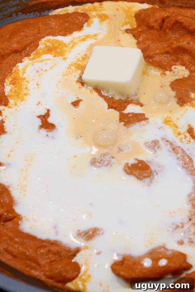 melted butter on top of butter chicken curry in large pan
