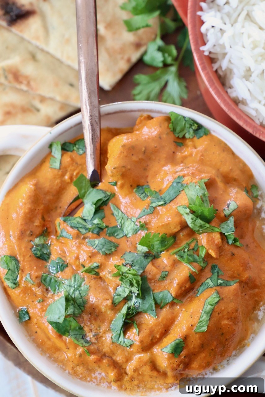 cooked chicken in butter curry sauce in bowl with spoon