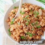 Kimchi fried rice in bowl with spoon and topped with diced green onions
