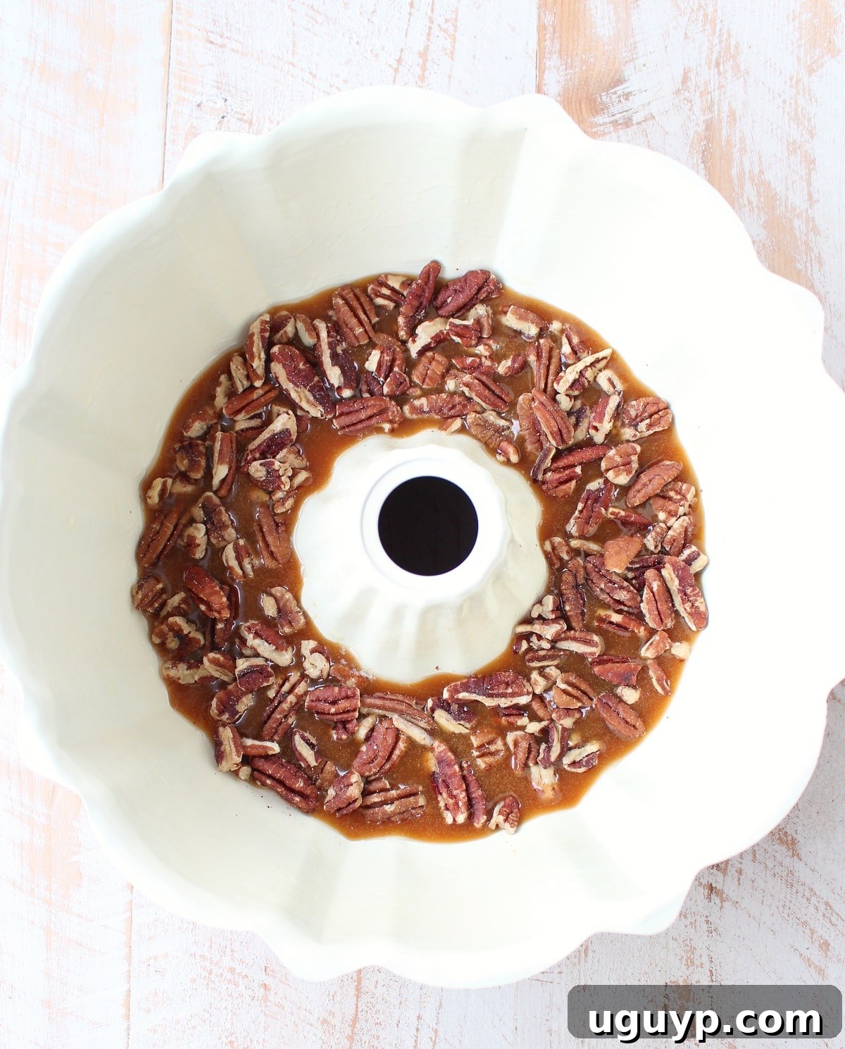 Caramel sauce and chopped pecans layered at the bottom of a bundt pan.