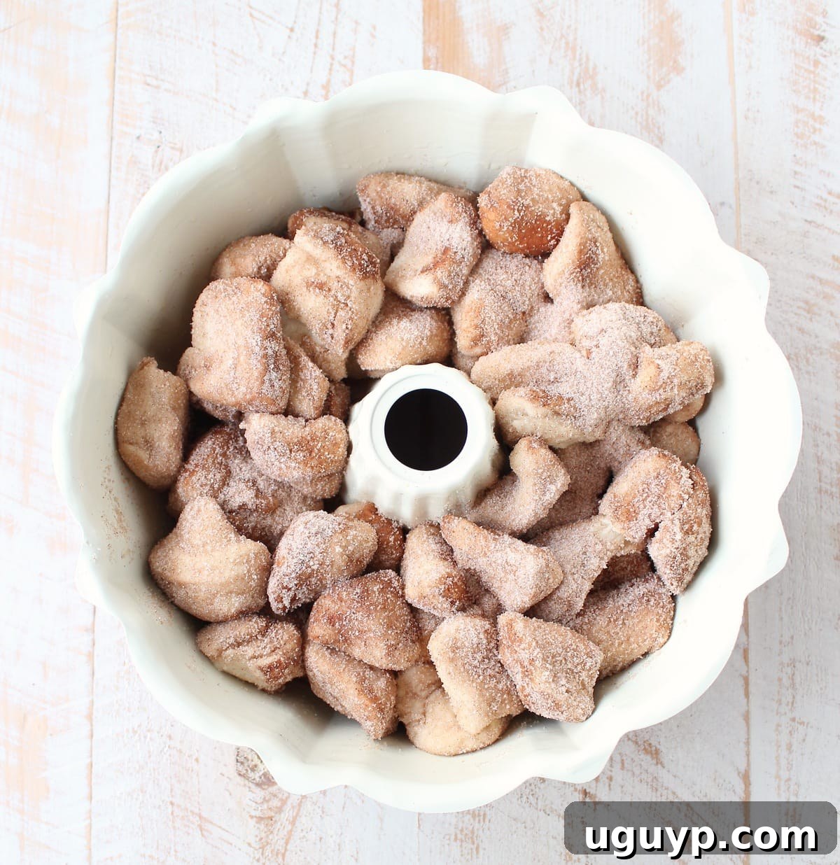 Biscuit pieces coated in cinnamon sugar, ready to be added to the bundt pan.