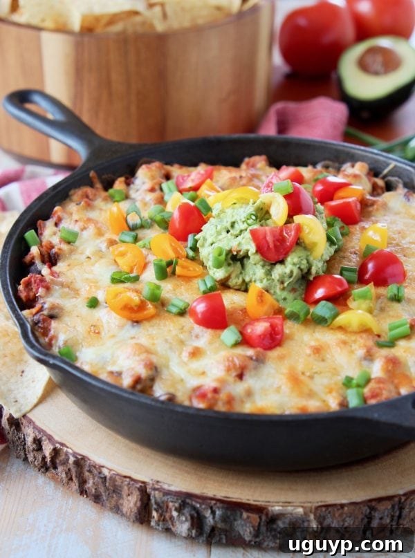 A delicious baked taco dip in a rugged cast iron skillet, presented on a rustic wooden cutting board, with crispy tortilla chips in the background, all resting on a festive red and white striped towel, perfect for a cozy gathering.