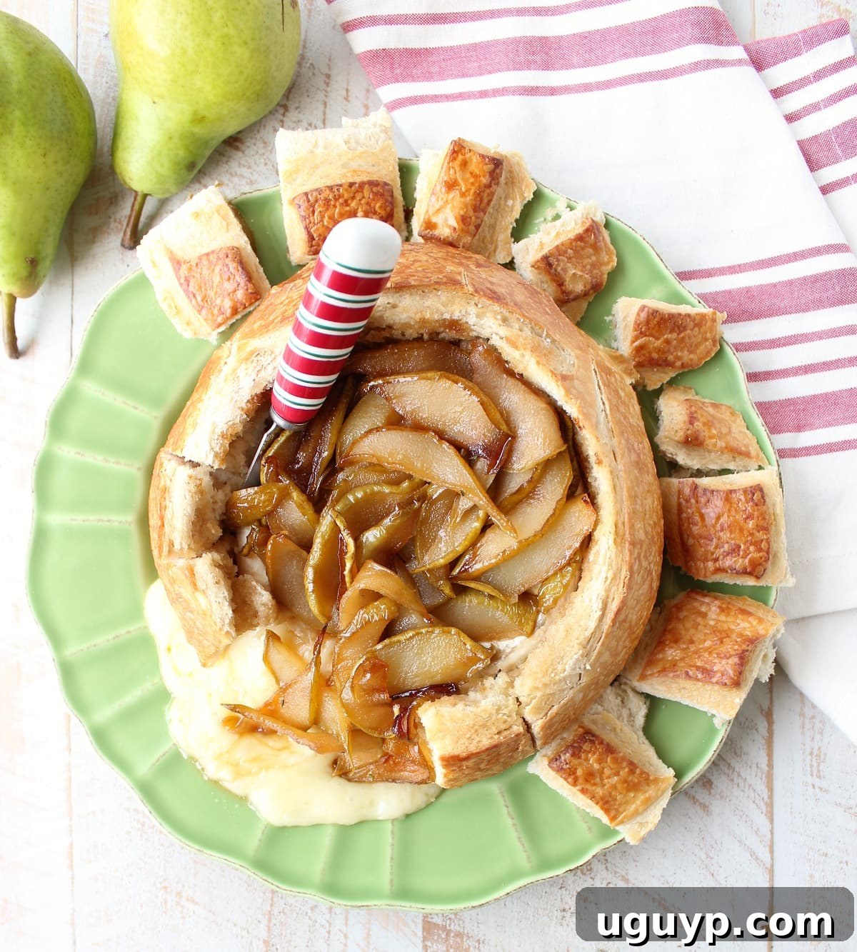 Sourdough bread bowl filled with melted baked brie, caramelized pears, and drizzled honey, ready to be served as a festive appetizer.