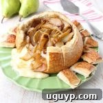 Caramelized Pear Baked Brie Sourdough Bread Bowl, fresh from the oven, with melted cheese and glistening pears.
