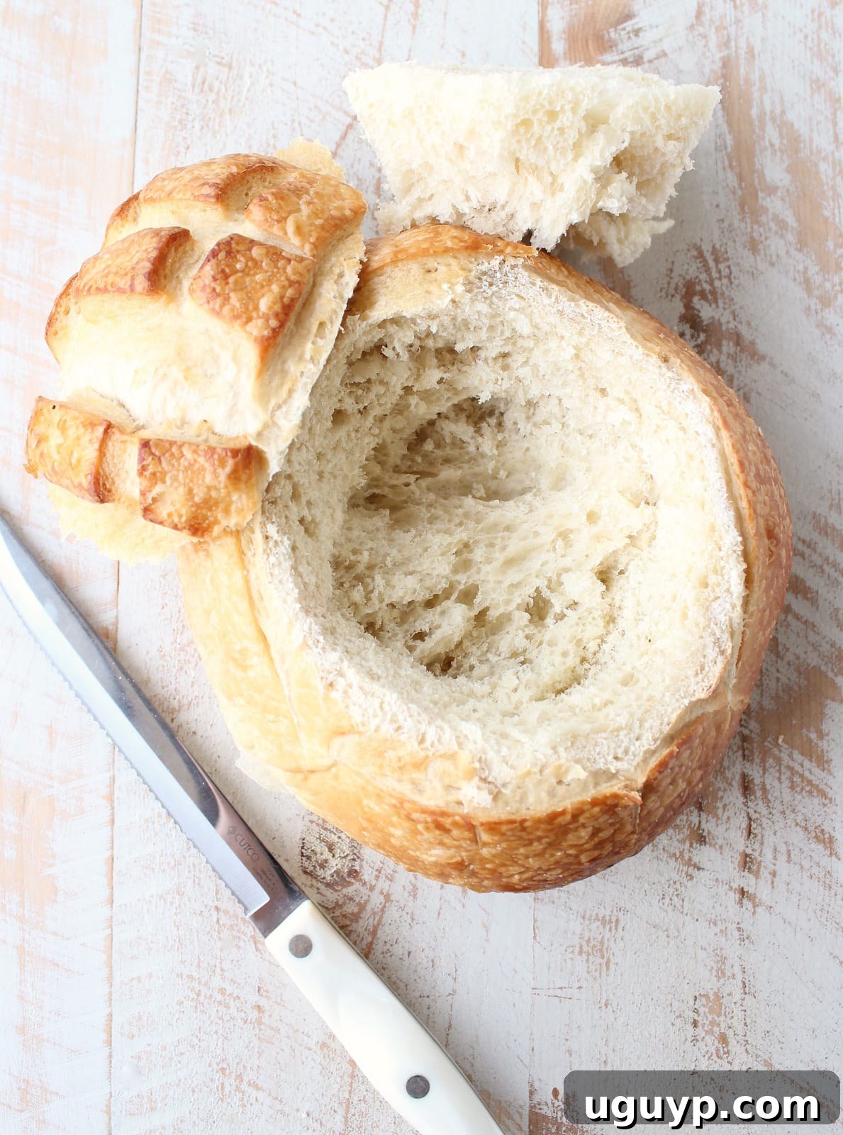 A sourdough bread round with its center carefully hollowed out, showing the perfect cavity for the brie cheese.