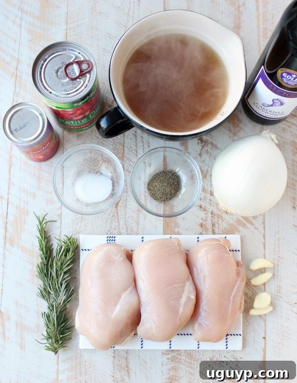 Fresh ingredients for slow cooker chicken ragu including onions, garlic, rosemary, chicken, and canned goods, arranged on a rustic wooden surface.