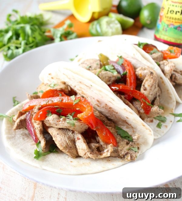 A vibrant platter of Jerk Chicken Fajitas, featuring perfectly seasoned chicken strips, colorful bell peppers, and red onions, ready to be wrapped in warm tortillas for a quick and easy weeknight dinner.