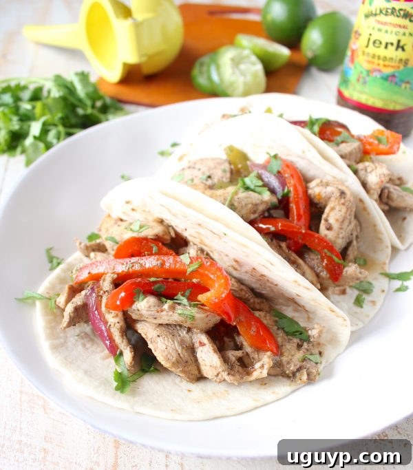 A freshly made Jerk Chicken Fajita, filled with seasoned chicken, colorful peppers, and onions, drizzled with sour cream or honey lime dressing, ready to be enjoyed.