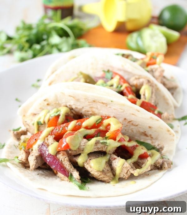 A close-up of a filled Jerk Chicken Fajita ready to be eaten, highlighting the textures of the chicken, vegetables, and soft tortilla.