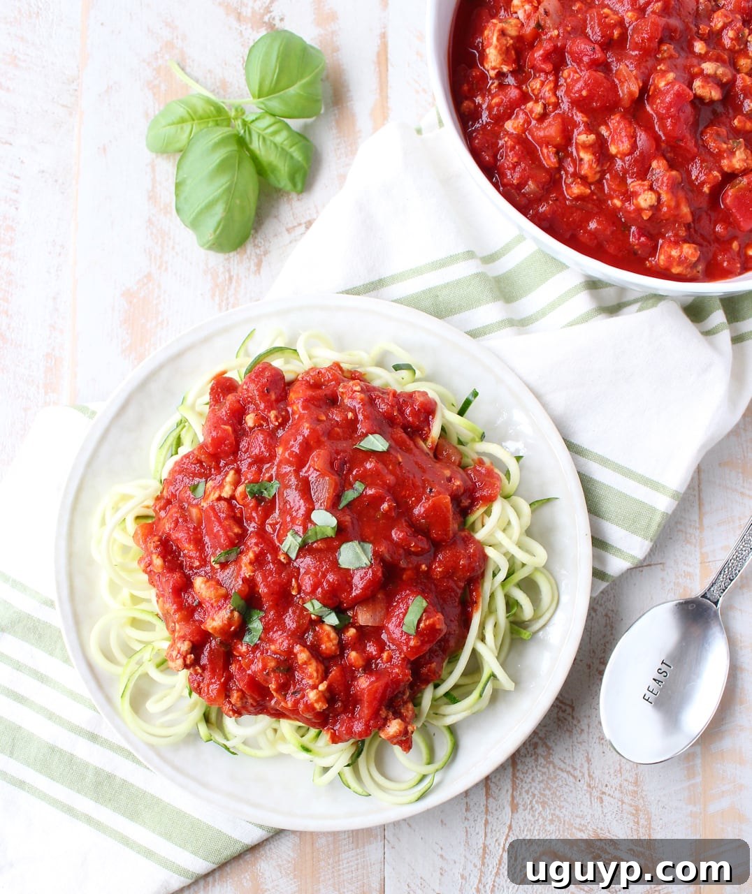 A hearty bowl of Roasted Red Pepper Turkey Bolognese served over zucchini noodles, garnished with fresh basil, showcasing a vibrant, rich sauce.