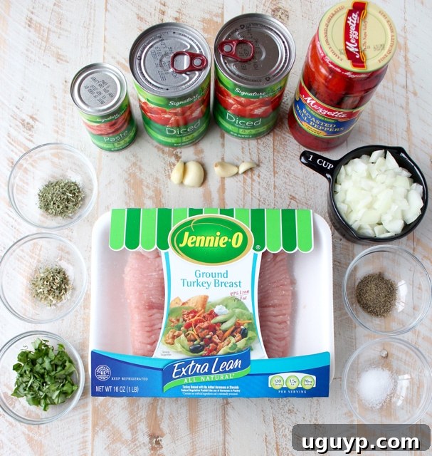 Fresh ingredients laid out on a white wooden board, including ground turkey, fresh basil, onion, garlic, canned tomatoes, and a jar of roasted red peppers, ready for a delicious turkey bolognese.