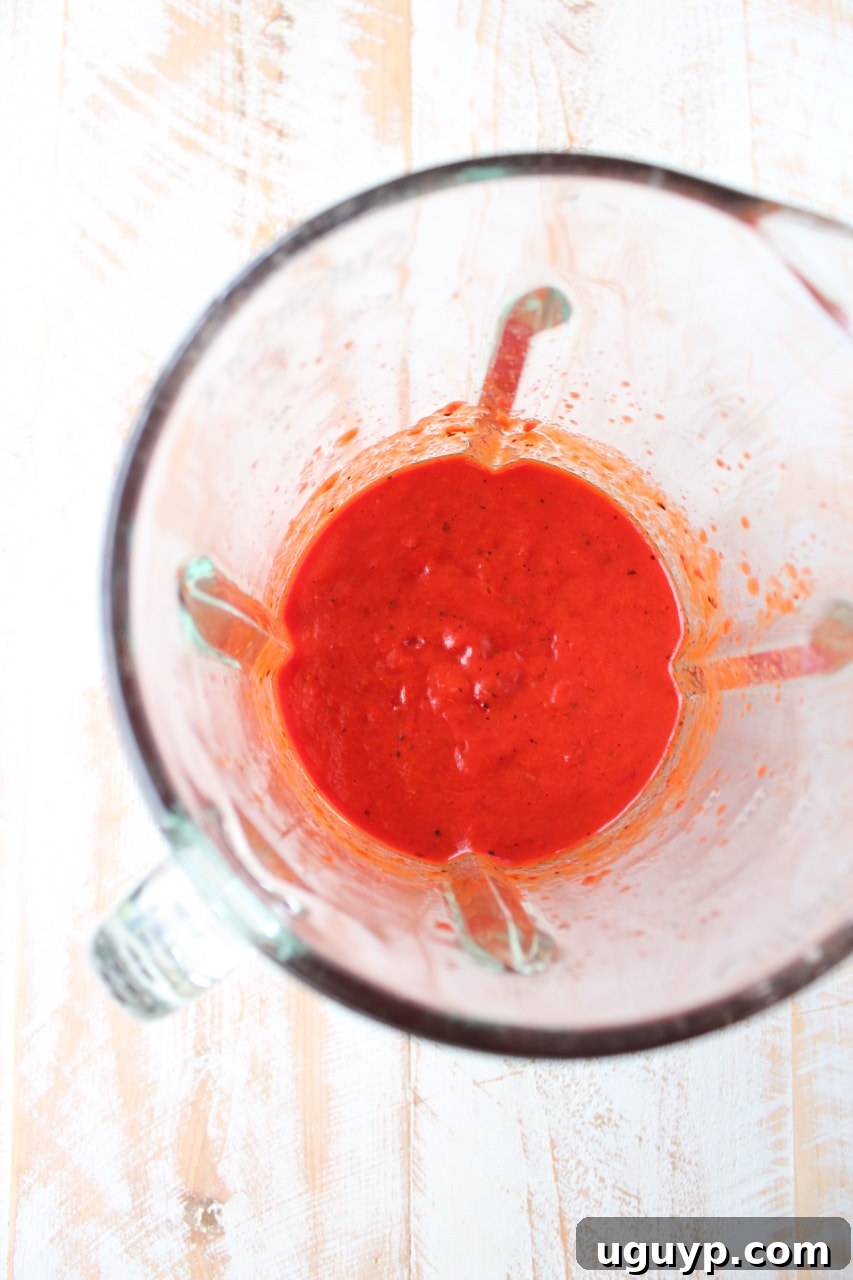 Pureed roasted red peppers in a blender, ready to be added to the bolognese sauce, showing a smooth, creamy texture.