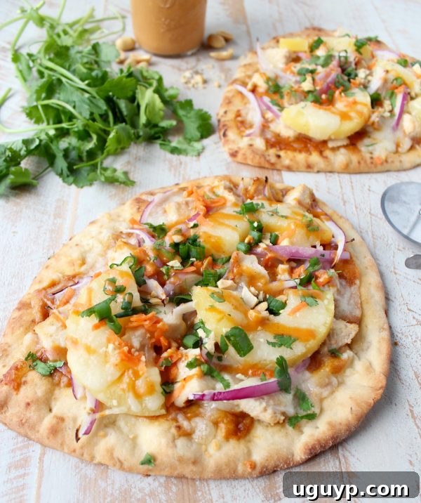 Close-up of a freshly baked Thai Peanut Chicken Naan Pizza, highlighting the golden crust and vibrant toppings.