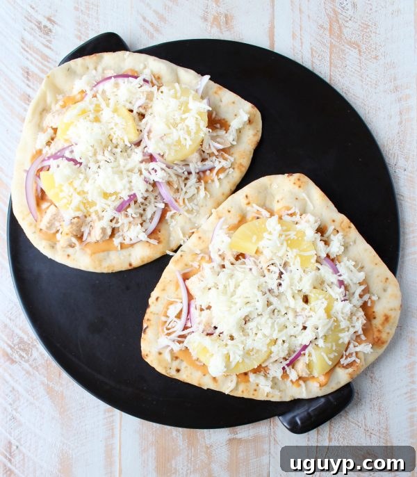Naan pizza ready for the oven, showcasing the colorful toppings and cheese.