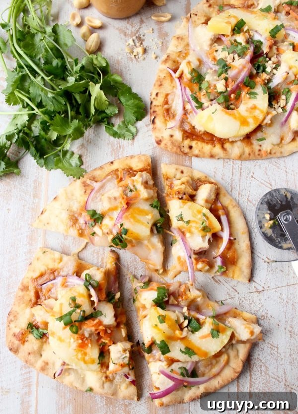 Sliced Thai Peanut Chicken Naan Pizza served with fresh lime wedges for an extra burst of flavor.